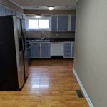 Modern kitchen with stainless steel appliances and wooden floor.