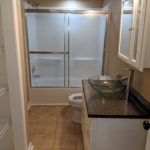 Modern bathroom with glass sink and sliding shower doors.