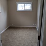 Empty room with beige carpet and a small window.