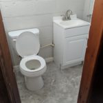A small bathroom with a toilet and a white sink cabinet.