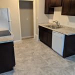 Modern kitchen with dark cabinets and tiled floor.