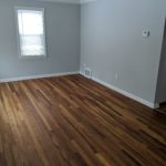 Empty room with wooden floor and gray walls.