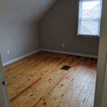 Empty room with wooden floors and a small window.